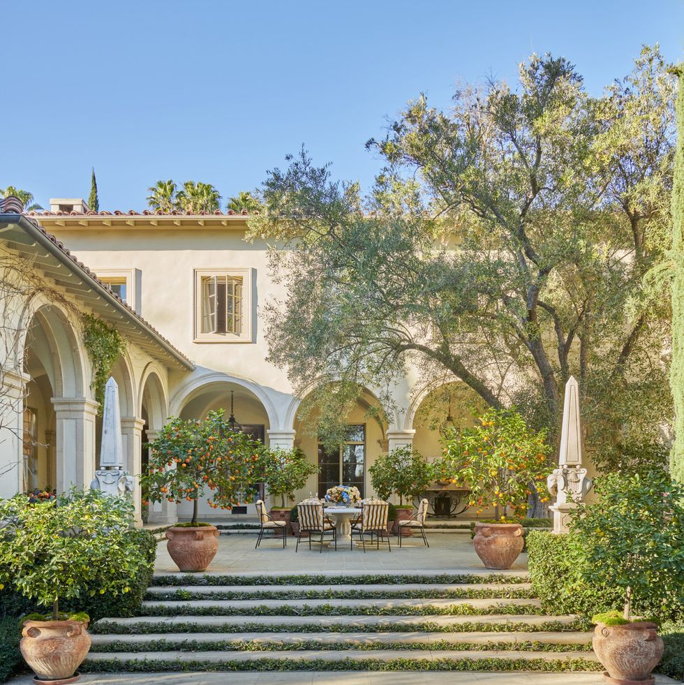 an olive tree shades the pool terrace furnished with a stone table and wrought iron chairs