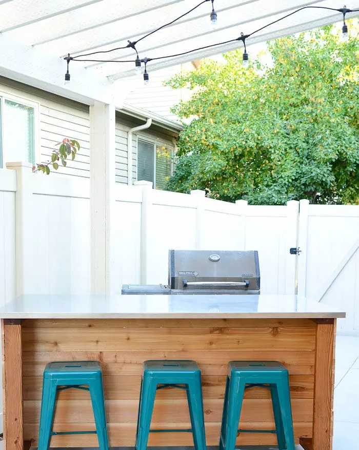 kitchen island idea on casters with a grill and three turquoise colored stools in front of it