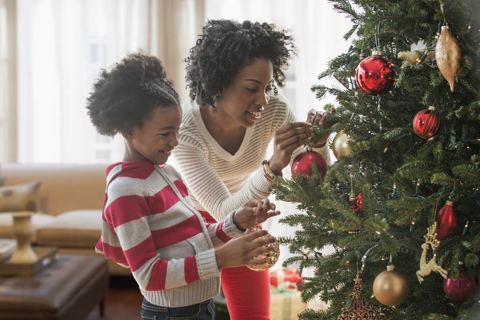 how long do christmas trees last, a woman and daughter putting ornaments on tree