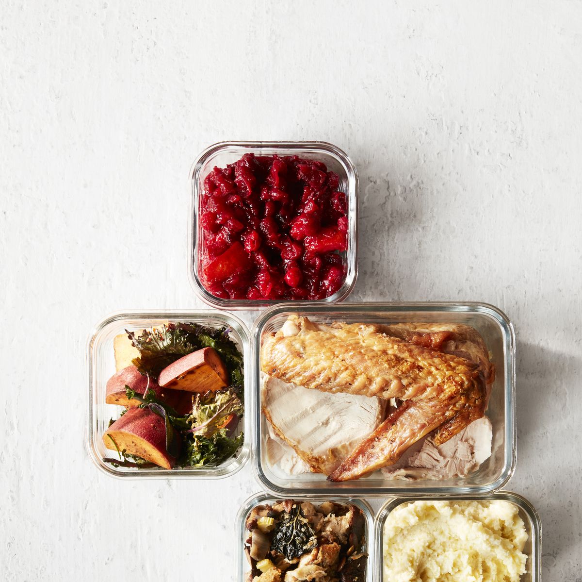 cranberry sauce, stuffing, mashed potatoes, turkey, greens and yams in leftover containers overhead