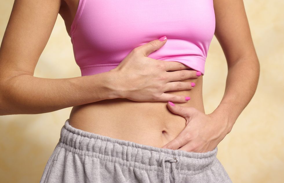 woman rubbing her stomach in pain