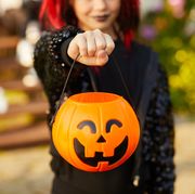 closeup of unrecognizable little girl wearing halloween costume and holding pumpkin basket in trick or treat season