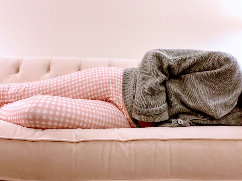wanita dewasa mencengkeram perut sambil berbaring di sofa