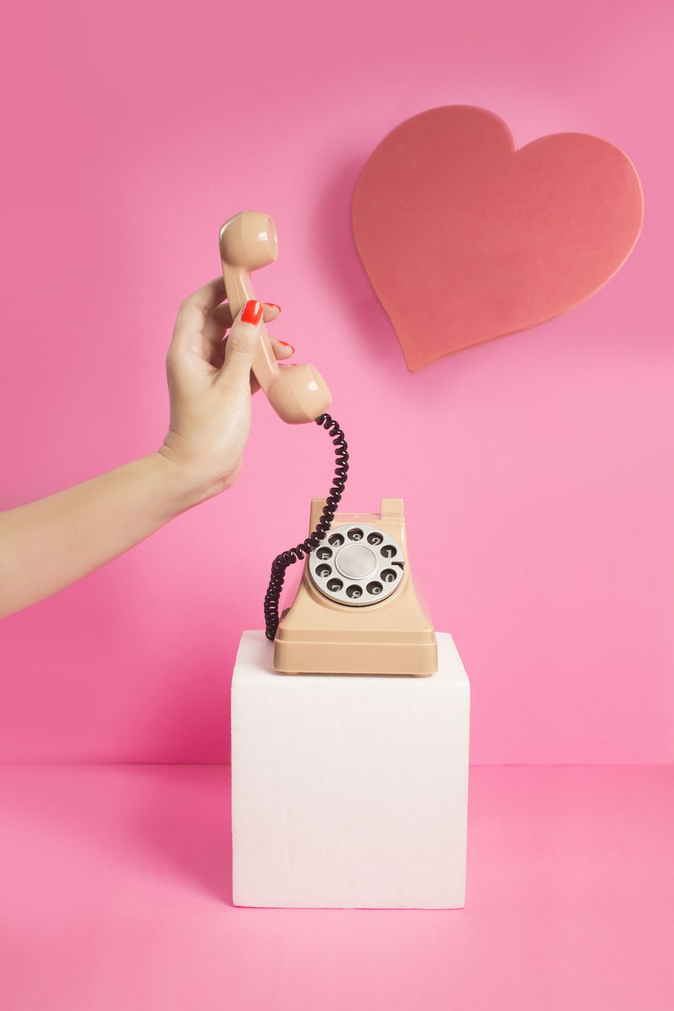 Traditional telephone on a pink background with a loveheart
