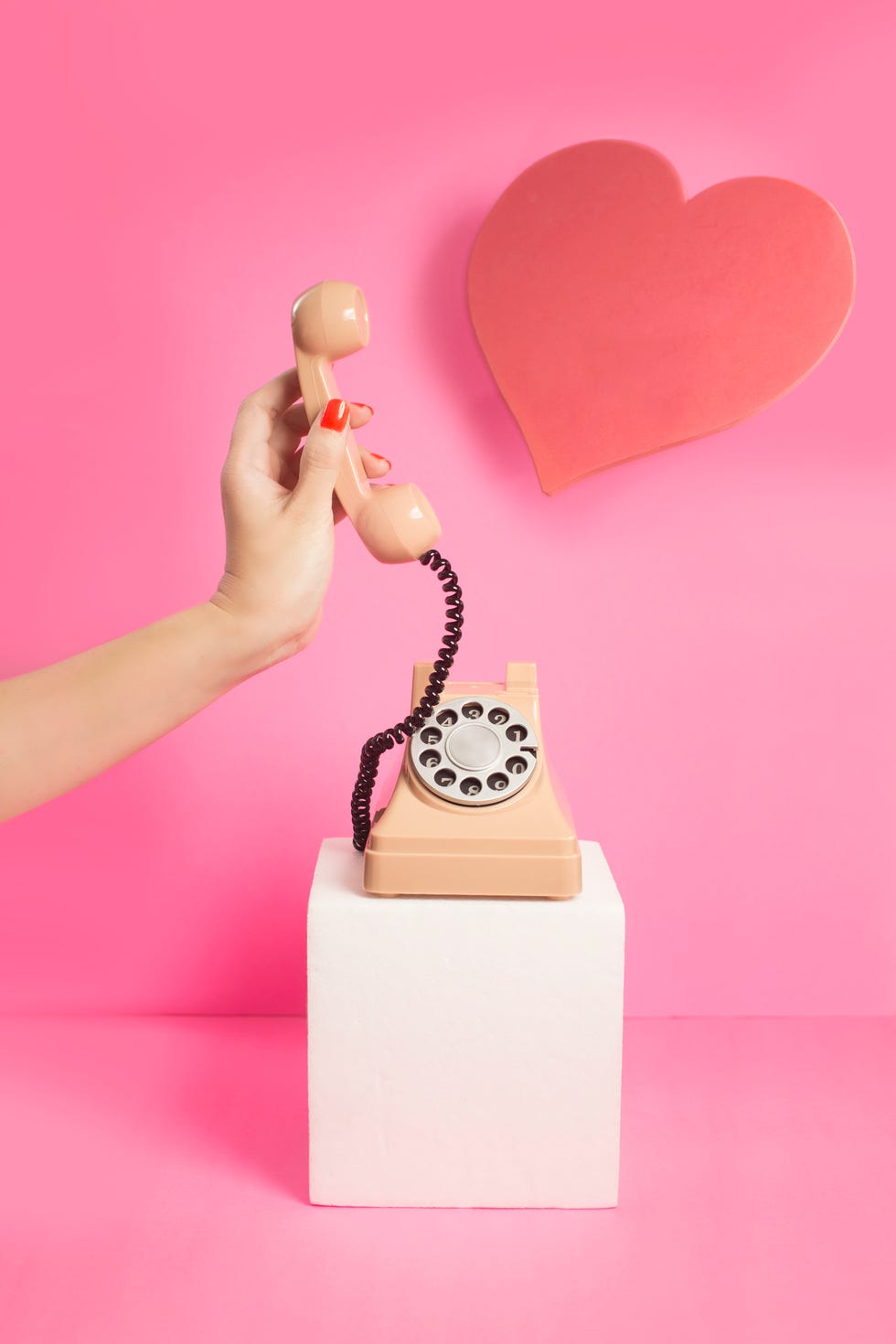 Traditional telephone on a pink background with a loveheart