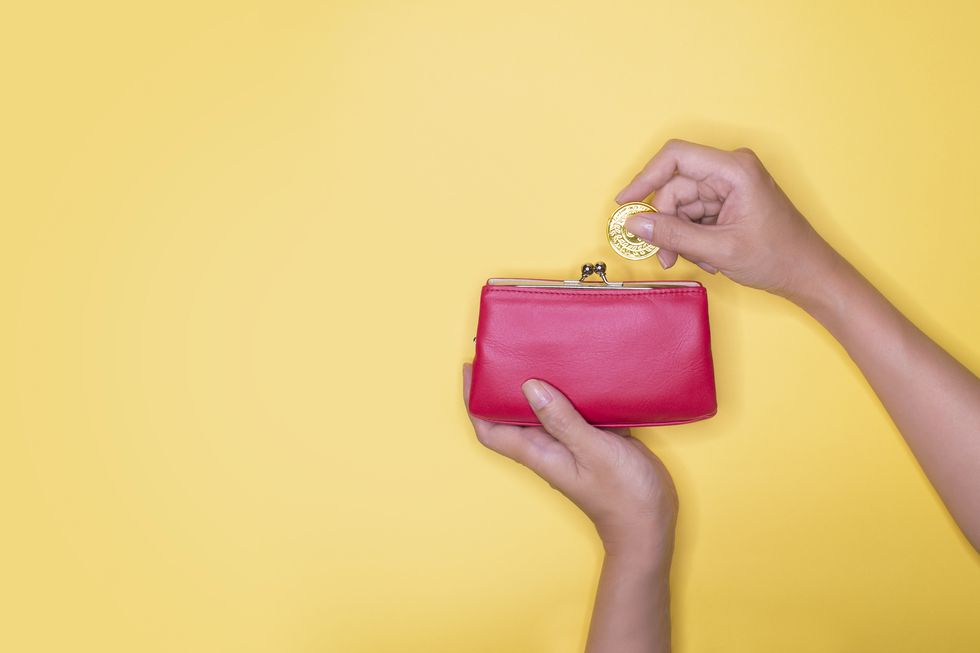 hand taking out or inserting coin into purse on yellow background