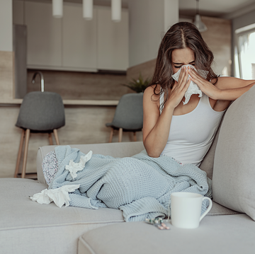 woman blowing her nose with a blanket and with tissues