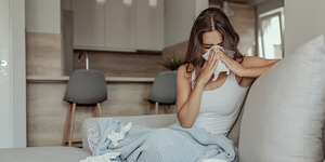 woman blowing her nose with a blanket and with tissues