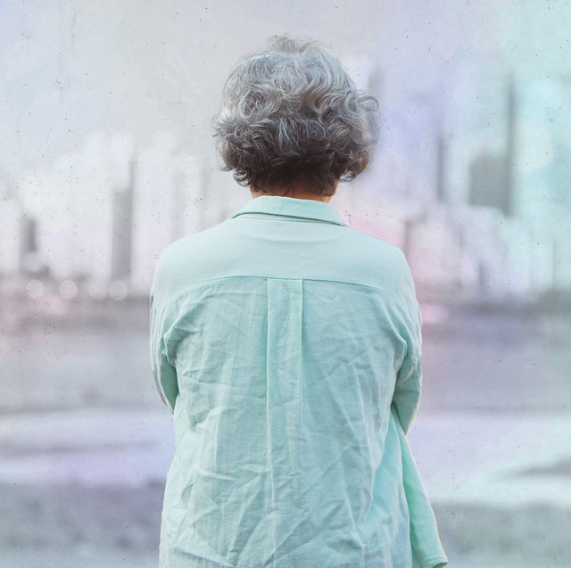 an older woman standing outside looking at a city skyline
