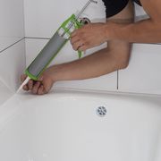 person caulking a bathtub