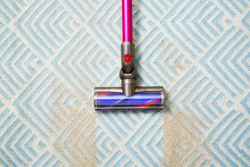 a vacuum cleaning sand off a blue and white carpet