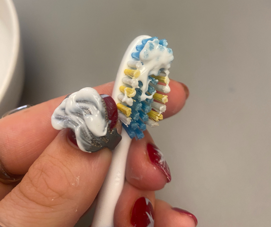 toothbrush with toothpaste applied held by a hand