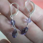 purple and silver earrings in hand