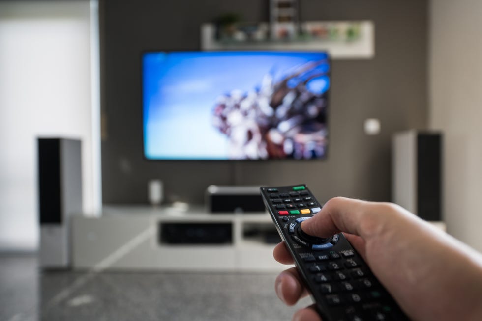 a man is switching through television channels captured inside a modern living room at daytime