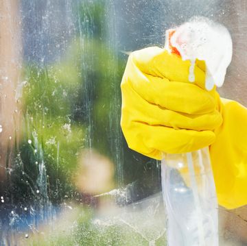 how to clean windows, hand in rubber glove washes home window from spray bottle