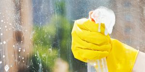 how to clean windows, hand in rubber glove washes home window from spray bottle