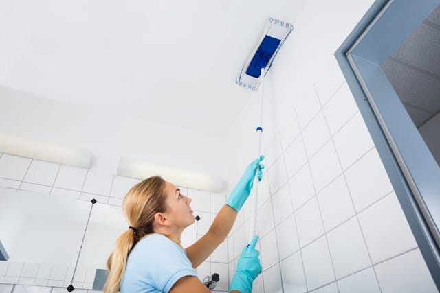 woman cleaning the ceiling of the bathroom with mop