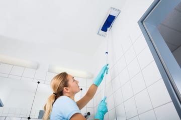 woman cleaning the ceiling of the bathroom with mop
