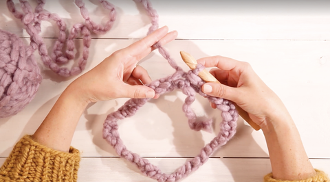 how to crochet for beginners, woman's hands creating a pom pom cowl