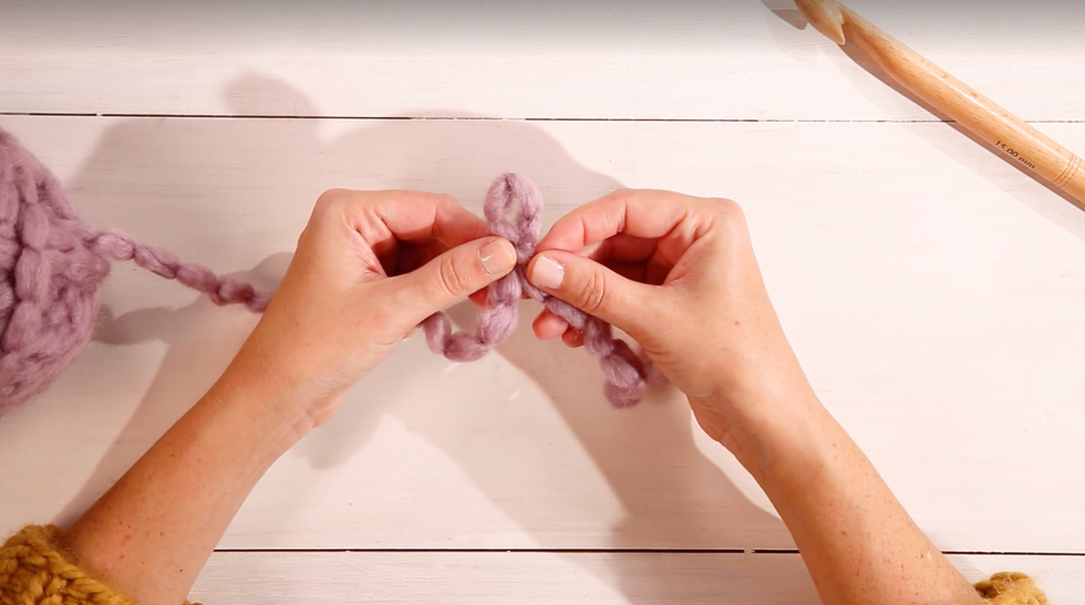 how to crotchet for beginners, woman's hand tying a knot in yarn