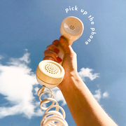 a phone held to the blue sky with the text "pick up the phone"