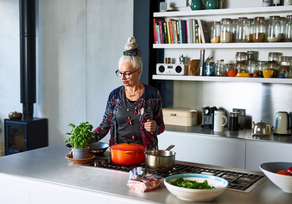 woman in her 60s with glasses preparing food in stylish kitchen, organisation, preparation, skill