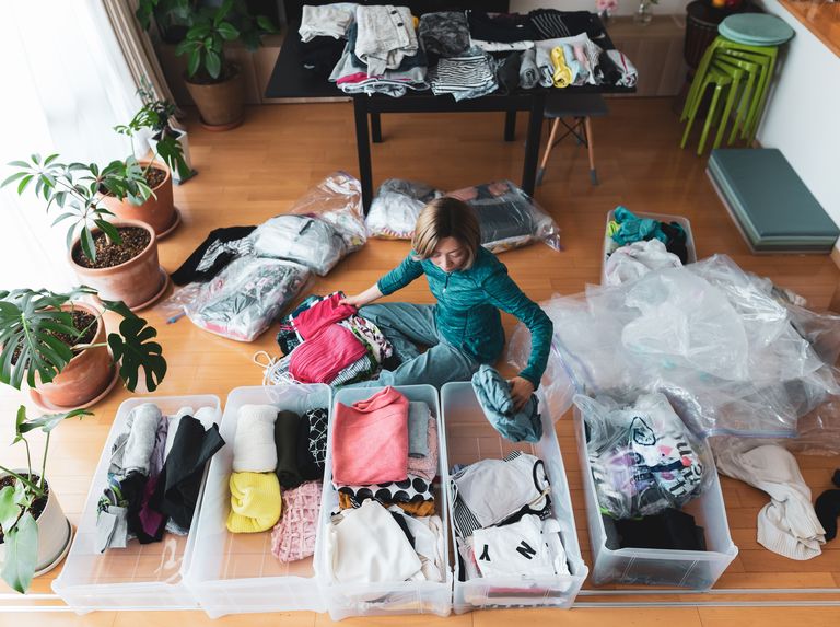 how to declutter clothes a woman organizes clothes in living room of her home