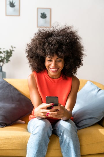 woman on couch smiling at smartphone