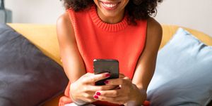 woman on couch smiling at smartphone