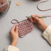 how to fasten off in crochet, woman crocheting with threads at grey table