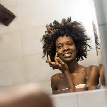 Woman applying face cream how to get rid of acne scars