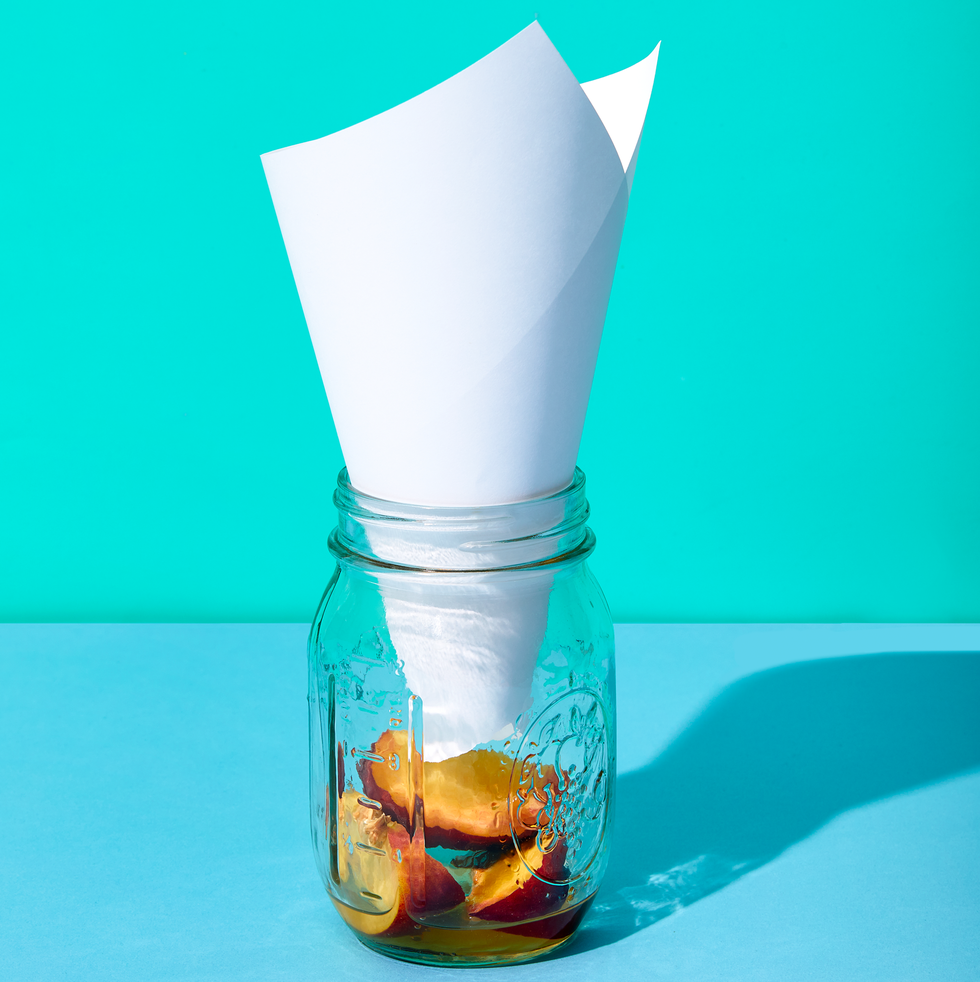 how to kill fruit flies, mason jar with cone shaped paper inside and rotting fruit at the bottom