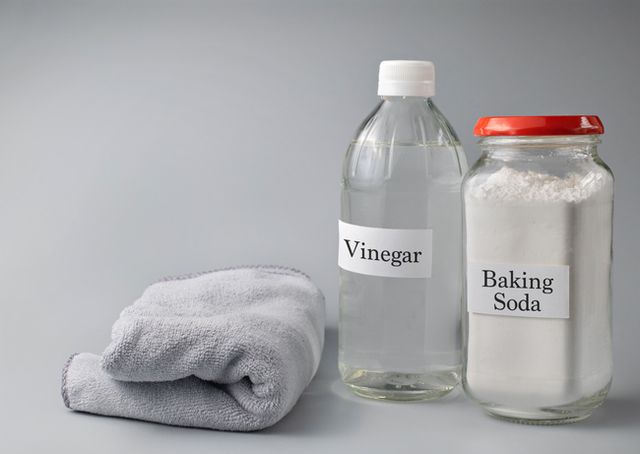 close up of vinegar and baking soda text on glass bottle against gray background