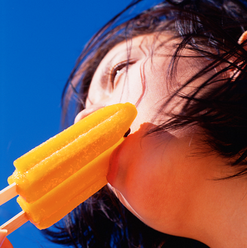 woman eating an orange popsicle