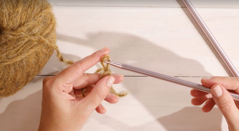 cómo tejer para principiantes, mujer creando un nudo corredizo con aguja de tejer e hilo