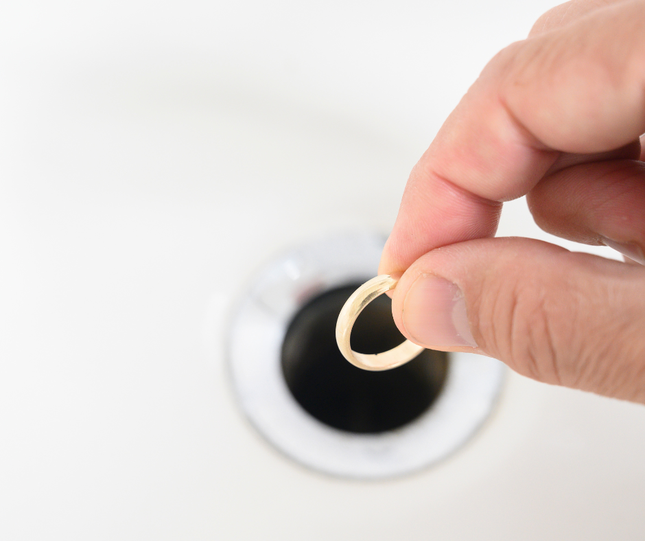 person holding a ring above a sink drain