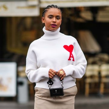 paris, france january 19 paola locatelli wears earrings, a white wool turtleneck ribbed pullover with printed red heart from ami, a black leather mini bag from ami, a beige mini skirt, white socks, black leather square toe ankle boots, outside ami, during paris fashion week menswear fw 2022 2023, on january 19, 2022 in paris, france photo by edward berthelotgetty images