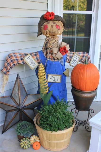 diy scarecrow on a front porch wearing overalls with sign reading happy fall y'all