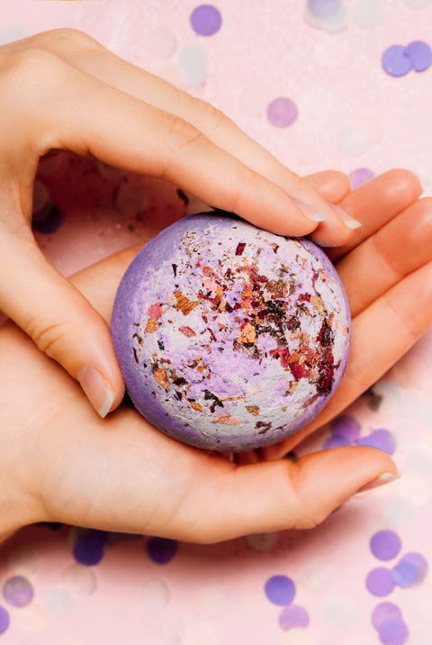 how to make bath bombs, flat lay of a bath bomb in girls hand with festive confetti