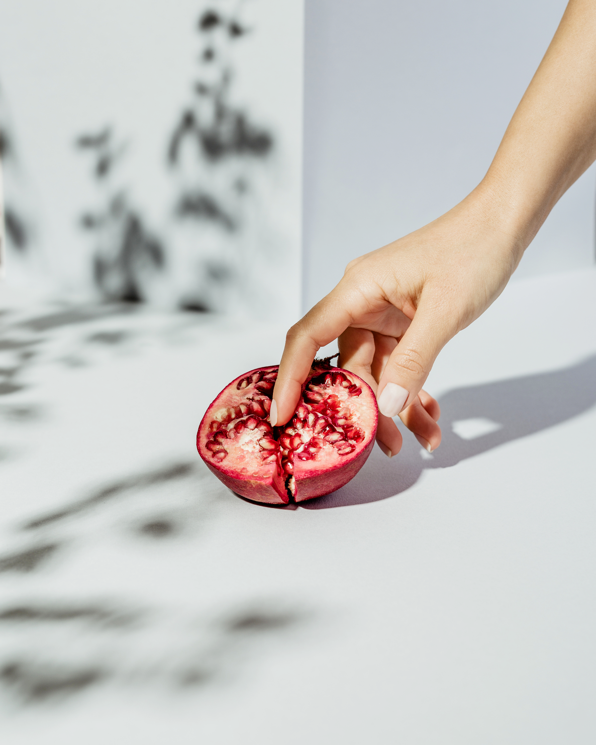 woman with a finger on a pomegranate