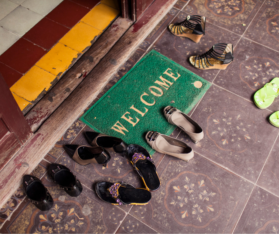 footwear scattered near a welcome mat at the entrance of a home