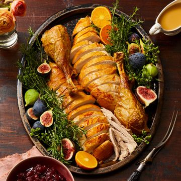 sliced thanksgiving turkey on a platter with figs and herbs