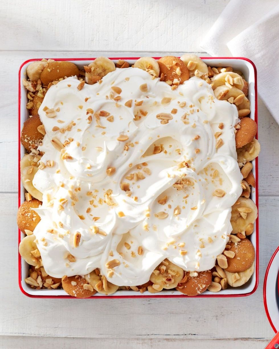 banana pudding with peanuts and whipped cream in a white dish with red trim