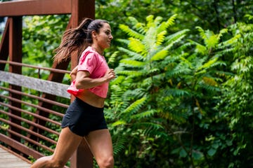 woman jogging on a bridge surrounded by greenery