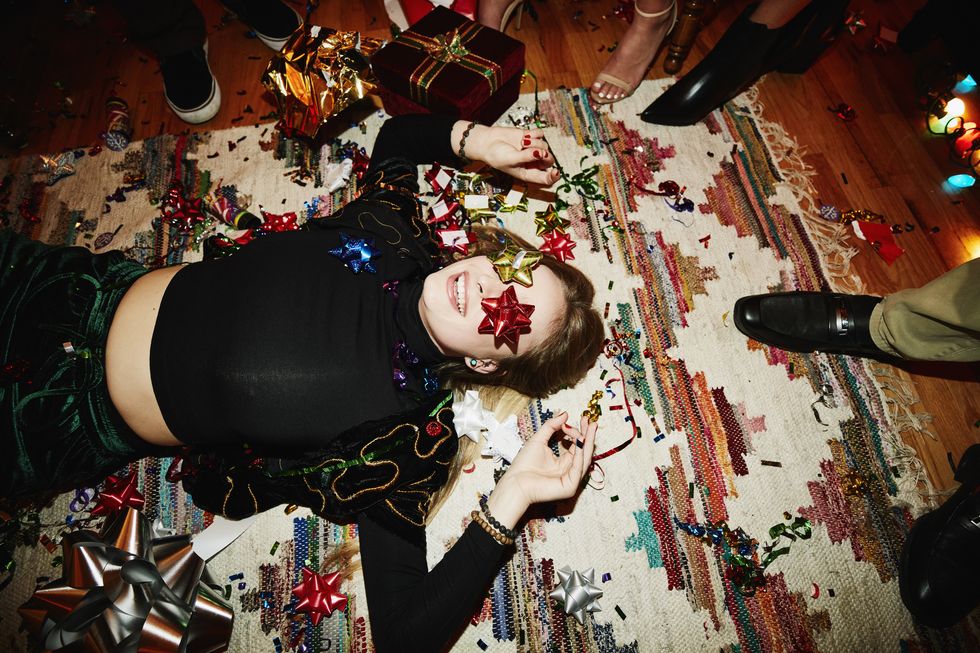 woman lying on carpet on floor at christmas party covered in tinsel