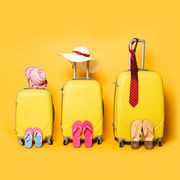 family travel bags with beach summer accessories on yellow