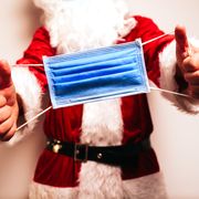 caucasian santa claus showing a surgical mask with both hands
