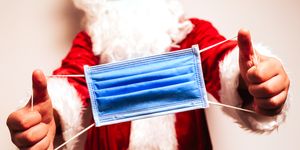 caucasian santa claus showing a surgical mask with both hands