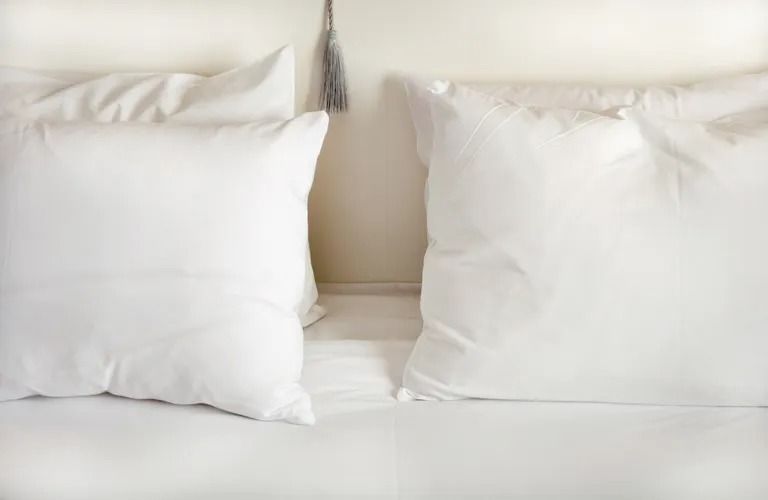 four white pillows on bed against a white headboard