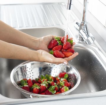 woman is washing strawberry in the kitchen